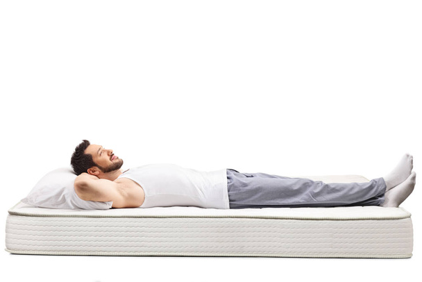 Young man wearing nightwear and lying on a mattress - Φωτογραφία, εικόνα