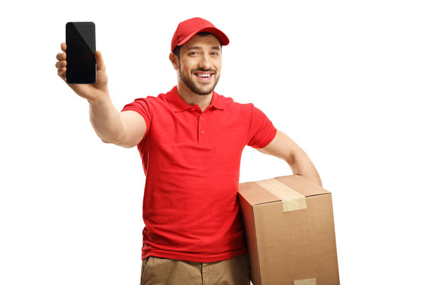 Smiling guy holding a package and showing a mobile phone - Photo, Image