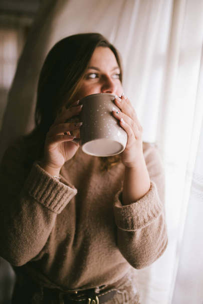 Fashion woman enjoying coffee or tea moment. Coffee cup in girl hands. Female with cup of hot beverage. Winter cup of drink. Relaxing concept. - Фото, изображение
