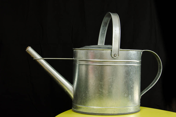 Old metallic watering can isolated in front of black background  - Photo, Image