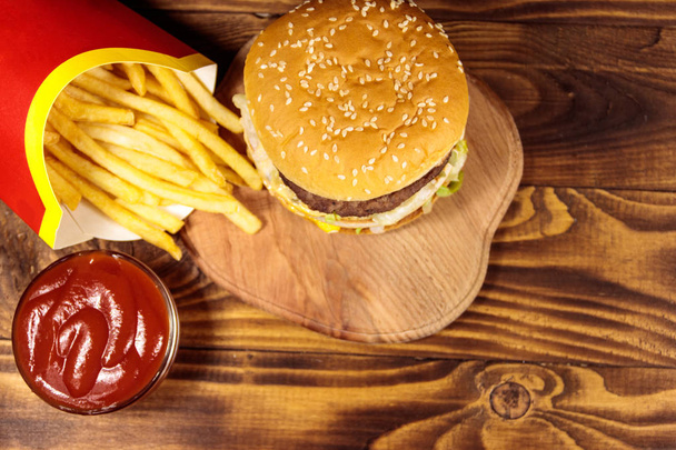Delicious big hamburger with french fries and ketchup on wooden table. Top view - Photo, Image