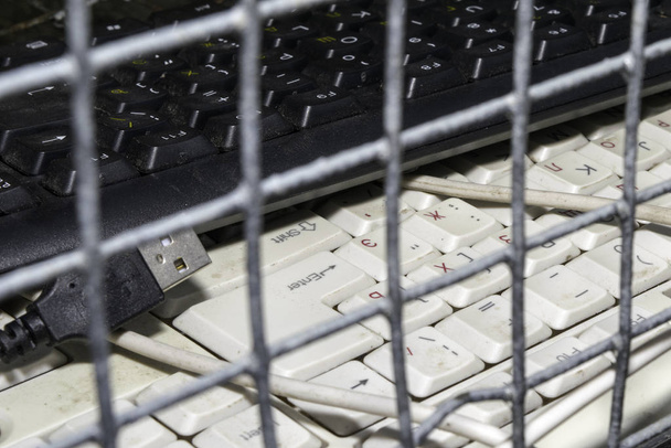 Verbote und Beschränkungen im Internet. Tastaturen aus dem Computer liegen in der Zelle hinter Gittern. Fokus auf Klack - Foto, Bild