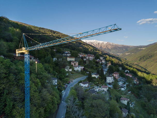Вид с воздуха на строительный кран в альпийской долине Швейцарии
 - Фото, изображение