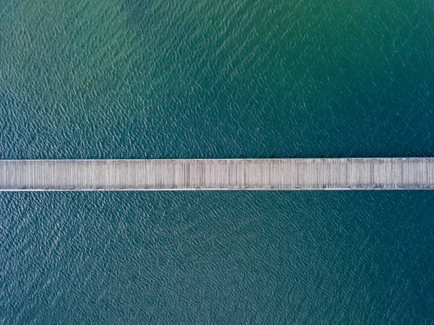 Vista aérea del puente peatonal sobre el lago. Puente de madera estrecho
 - Foto, imagen