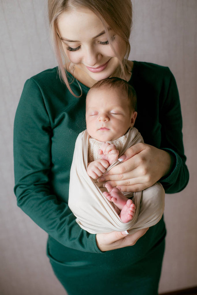 Young beautiful blond hair mamaso with a baby in her arms at home. Happy motherhood - Foto, Imagen