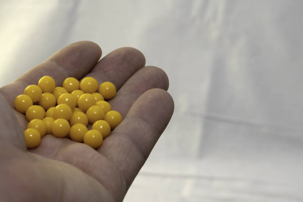 mano sosteniendo un puñado de pastillas amarillas
 - Foto, Imagen