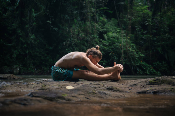 Práctica de yoga y meditación en la naturaleza. Hombre practicando cerca del río
 - Foto, imagen