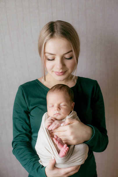 Joven y hermosa mamaso pelo rubio con un bebé en sus brazos en casa. Feliz maternidad.
 - Foto, Imagen