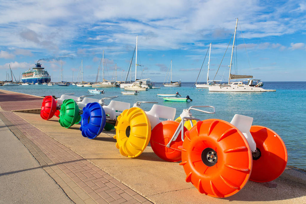 Педальные лодки и парусные лодки у моря с бульваром
 - Фото, изображение