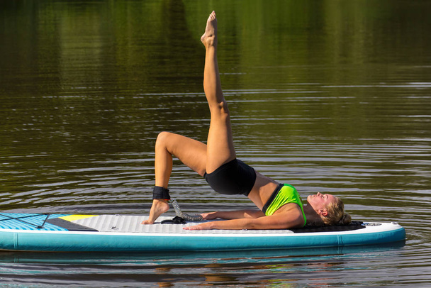 Femme en pose de yoga jambe vers le haut sur SUP
 - Photo, image
