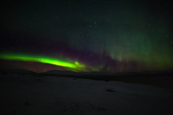 Drámai sarki fények, Aurora borealis sok felhők és csillagok az égen a hegyek felett Észak-Európában - Abisko, Svédország. hosszú záridő. - Fotó, kép