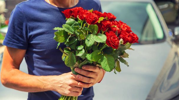 Букет красных роз в руках мужчины. Селективный фокус
. - Фото, изображение