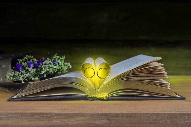 Νεκρή φύση Σημάδι καρδιάς με βέρα σε βιβλίο κειμένου σε καρτέλα ξύλου - Φωτογραφία, εικόνα