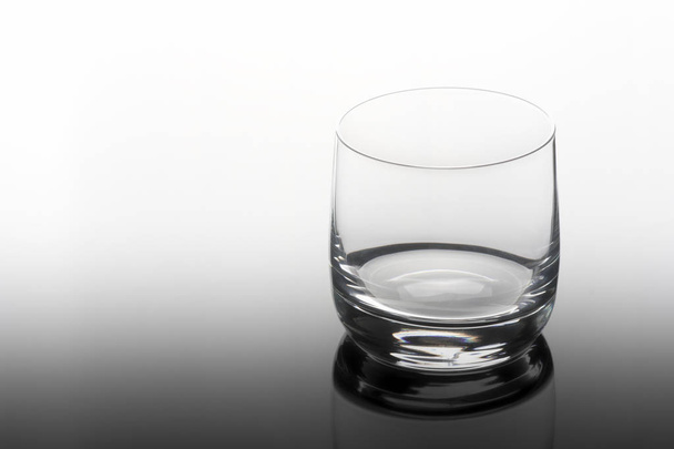 Κενό ποτήρι για ουίσκι, μπράντι ή μπέρμπον σε διάφανο τραπέζι. - Φωτογραφία, εικόνα