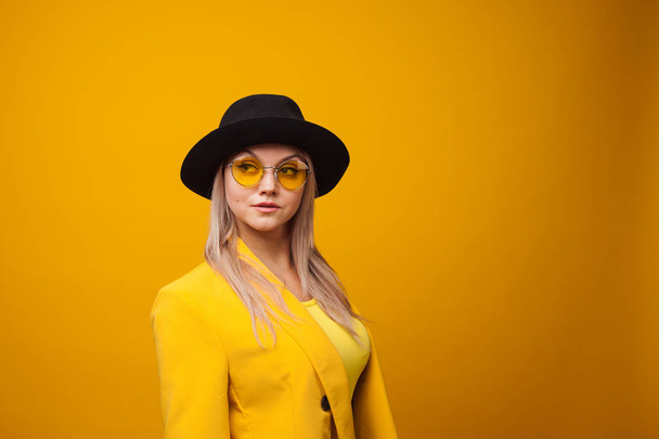 Stylish trending young woman in bright clothes on yellow background, copy space. Cool blonde - Foto, Bild