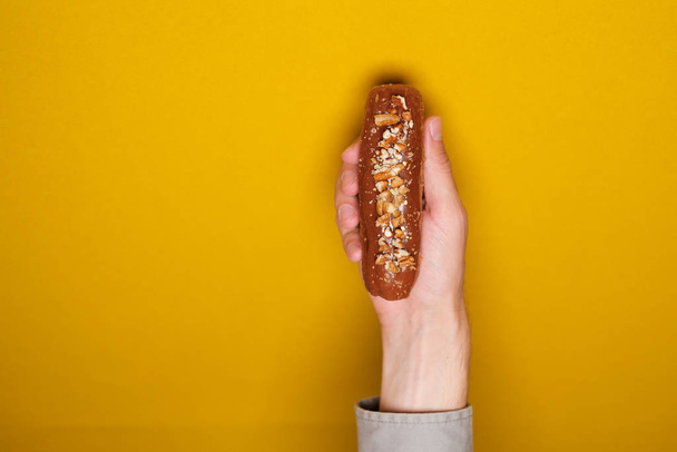 Person hand holding sweet eclair, close view  - Photo, image