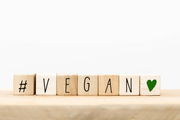 Wooden cubes with a Hashtag and the word vegan, social media concept background - Photo, Image