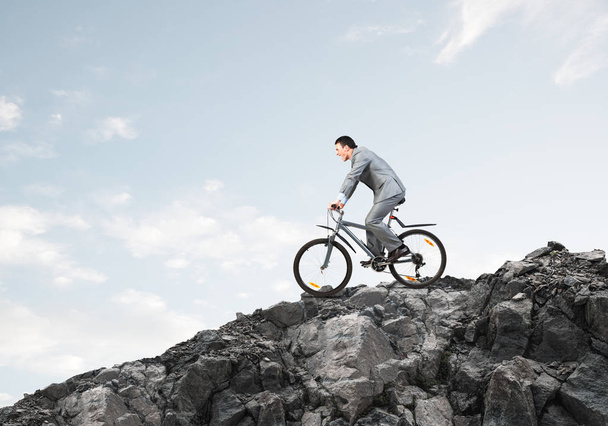 Zakenman rijdt Downhill op de fiets. Natuur landschap met Kopieer ruimte. Man in Business Suit rijden fiets op bergweg. Fietser op de achtergrond van de blauwe lucht. Gezonde levensstijl en buitenactiviteiten - Foto, afbeelding