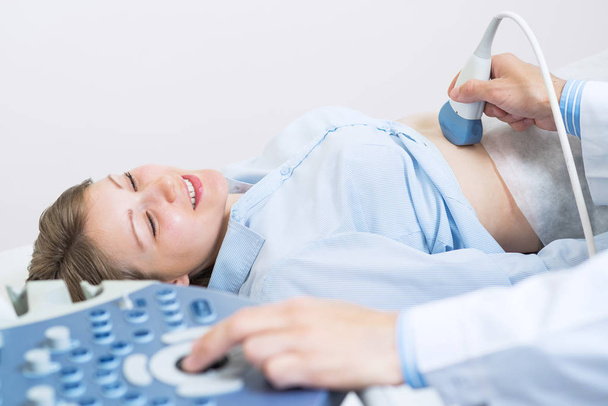 Portrait of happy woman at ultrasound examination. Professional diagnostics and computer screening. Abdominal cavity diagnosis with modern equipment. Regular examination and disease prevention. - Foto, Imagem