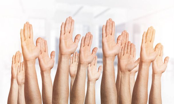 Una fila di mani d'uomo che mostra un gesto di voto. Partecipazione e accordo gruppo di segni. Mani umane che gesticolano su sfondo chiaro e sfocato. Molte braccia alzate insieme e presentano il gesto popolare
. - Foto, immagini