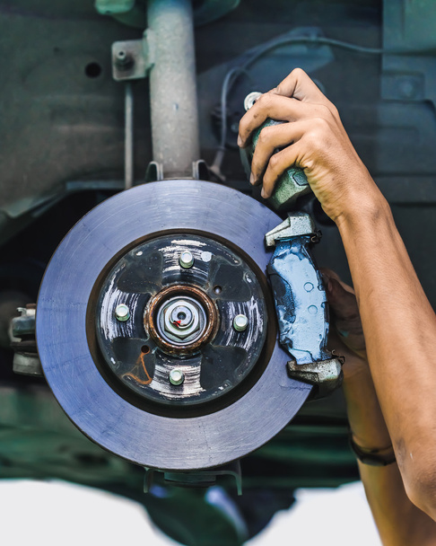 As mãos de um mecânico instalam o revestimento de freio em um freio de disco de carro
 - Foto, Imagem