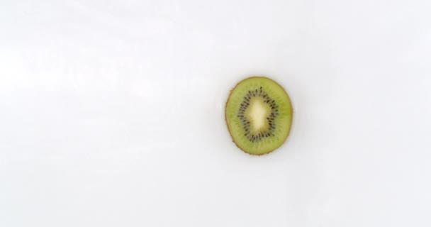 Slow motion water splash on one slice of kiwi lying on a white background in water. - Footage, Video