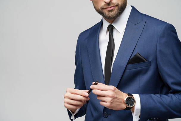 close-up photo of young businessman wearing suit holding pen - Fotó, kép