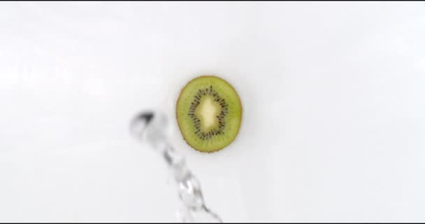 In slow motion, water splashes pour water onto one kiwi on a white background. Vegetarian and Fructorians - Footage, Video