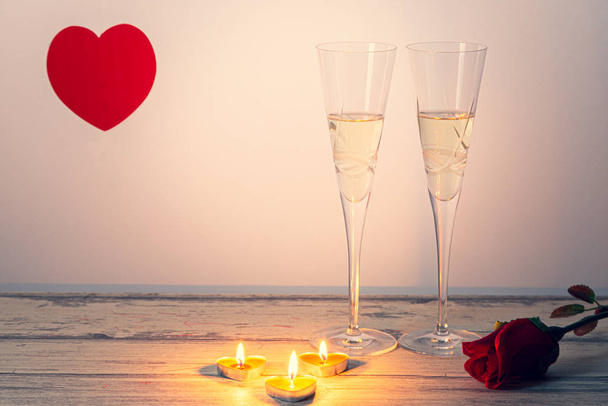 Σύνθεση ημέρας του Αγίου Βαλεντίνου με δύο ποτήρια σαμπάνια, καρδιά, τριαντάφυλλο και κεριά σε λευκό ξύλινο φόντο. Σαν Βαλεντίν και αγάπη έννοια. - Φωτογραφία, εικόνα