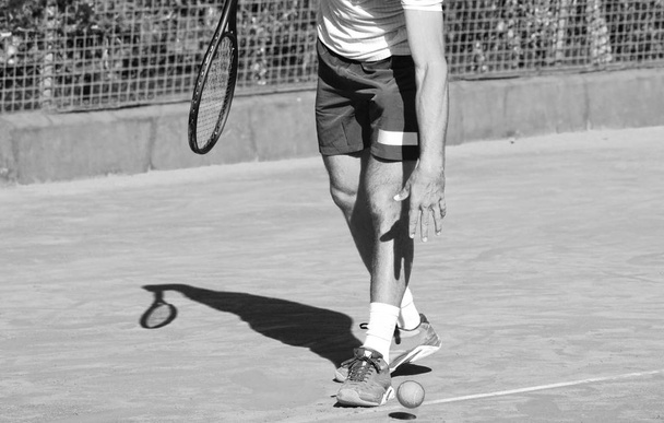 Monochromatyczne ujęcie z bliska profesjonalnego tenisisty z rakietą i piłką tenisową. - Zdjęcie, obraz