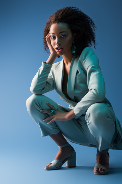 attractive african american woman in elegant suit on blue background  - Фото, зображення