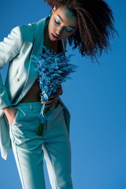 attractive african american woman holding bouquet isolated on blue - Fotó, kép