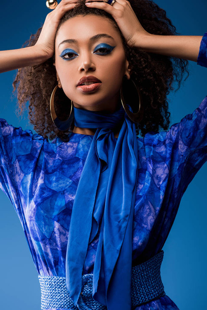 attractive african american woman in stylish dress looking at camera isolated on blue  - Zdjęcie, obraz