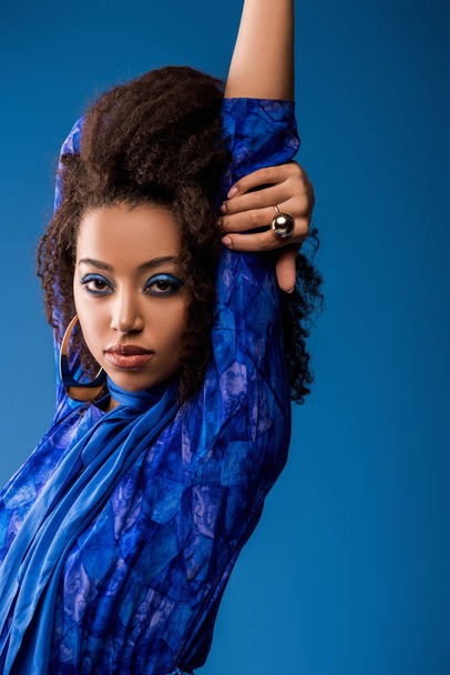 стильна афроамериканська жінка в одязі дивиться на камеру ізольовано на синьому
  - Фото, зображення
