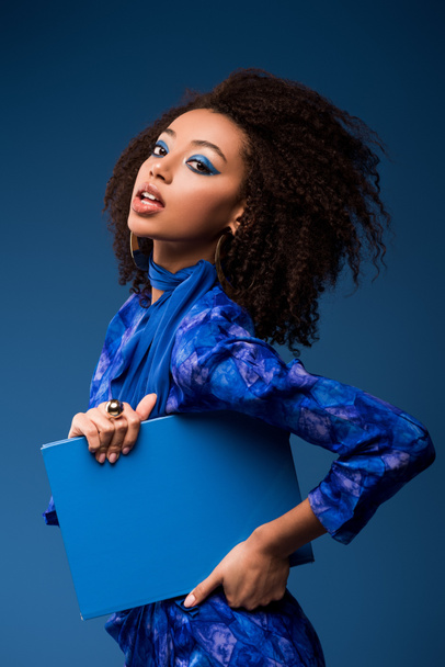 привлекательный африканский американец женщина держит папку изолированы на синий
  - Фото, изображение