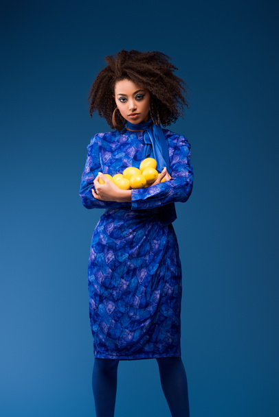 attractive african american woman holding lemons isolated on blue  - Foto, Bild
