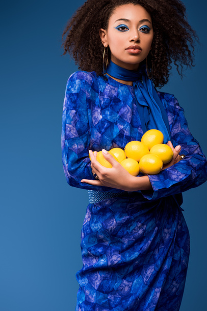 houkutteleva afrikkalainen amerikkalainen nainen tilalla sitruunat eristetty sininen
  - Valokuva, kuva