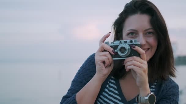 portret dziewczyny z kamerą retro. Młoda kobieta robi zdjęcia na Vintage kamery przez Ocean - Materiał filmowy, wideo
