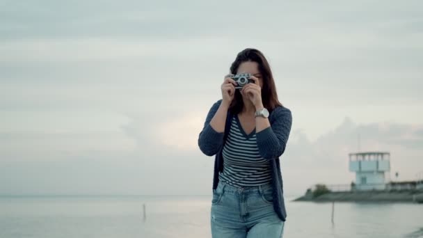 young woman takes photos on a retro camera outdoors. - Video
