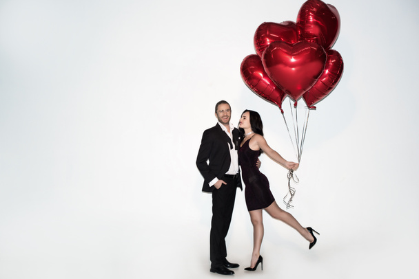 beautiful positive couple holding red heart shaped balloons on valentines day on white - Photo, Image