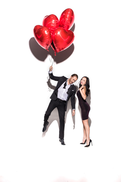 beautiful cheerful couple holding red heart shaped balloons on valentines day on white - Photo, Image