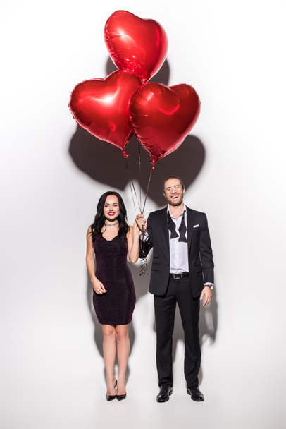 gyönyörű mosolygós pár kezében piros szív alakú lufik Valentin nap fehér - Fotó, kép