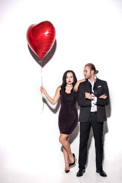 jong paar met rode hartvormige ballon op Valentijnsdag op wit - Foto, afbeelding