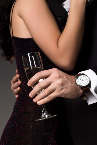 partial view of couple hugging and holding glass of champagne, isolated on grey - Fotografie, Obrázek
