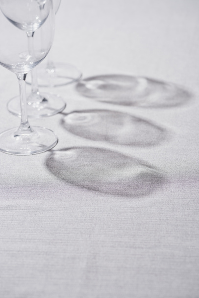 Прозорі келихи для вина з тіні на сірій скатертині
 - Фото, зображення