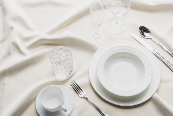 High angle view of dinnerware with glasses and coffee cup on white tablecloth - Foto, imagen