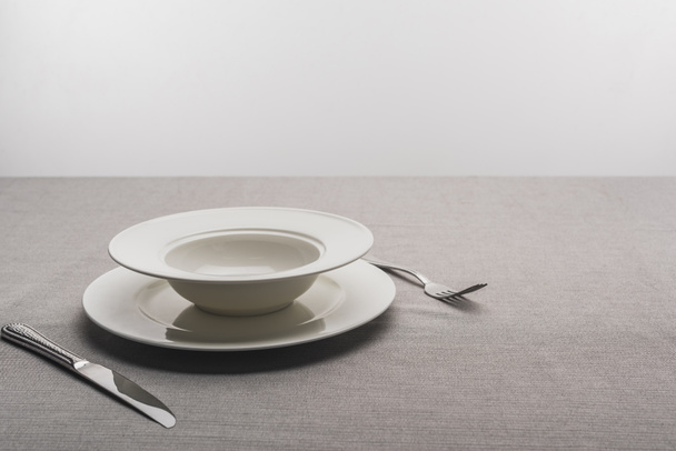 Plates with fork and knife on tablecloth on grey background - Foto, Imagem