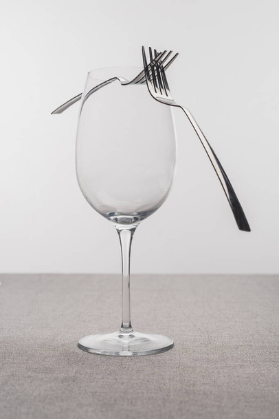 Two forks on clear wine glass on tablecloth isolated on grey - Photo, Image