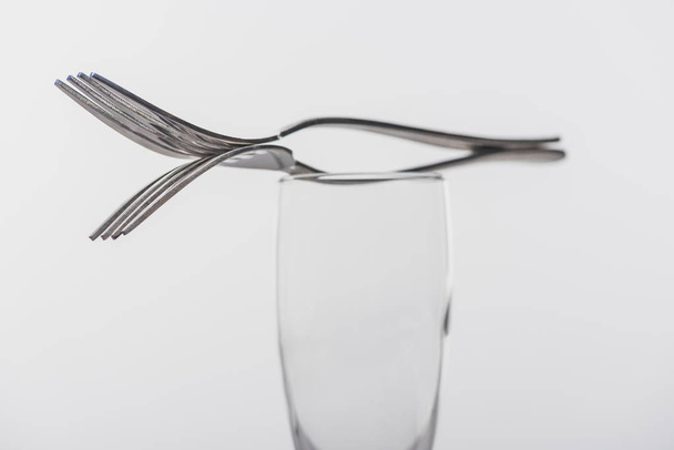 Selective focus of forks on clear champagne glass isolated on grey - 写真・画像
