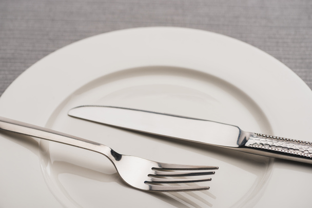 Lähikuva ruokailuvälineet tyhjälle lautaselle harmaalla pinnalla
 - Valokuva, kuva